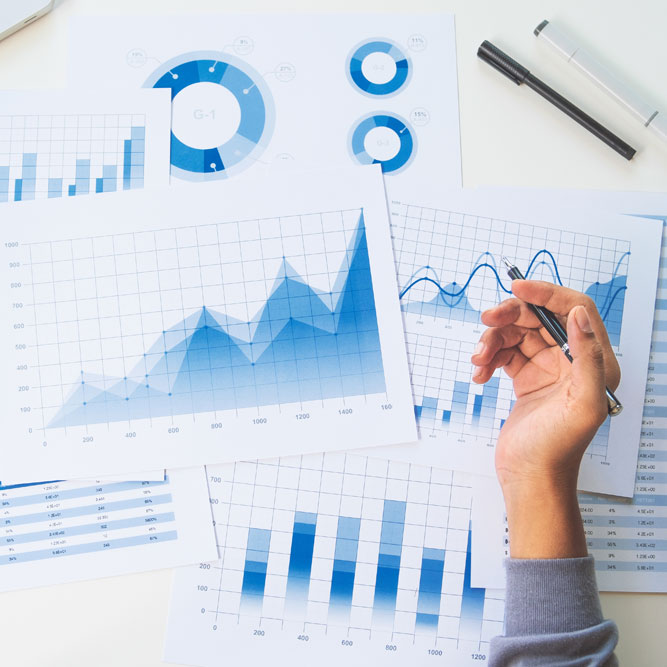 hand holding a pen over top of reports